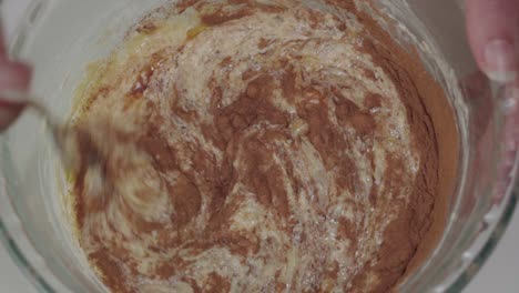 Mixing-cinnamon-and-vanilla-extract-into-yellow-batter,-Closeup-from-Above
