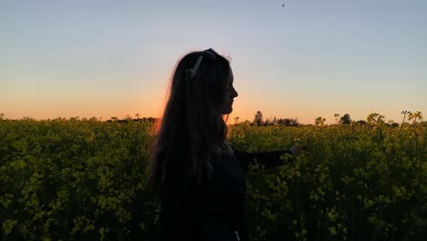 Girl-with-sunglasses-walking-near-raspeed-field-during-sunset