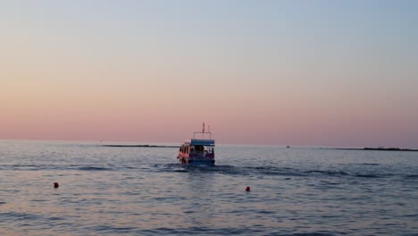 Malerischer-Blick-Auf-Ruhiges-Ozeanwasser-Und-Boot,-Das-Bei-Sonnenuntergang-Vom-Ufer-Wegfährt,-Reifen,-Libanon,-Schwenk-Links