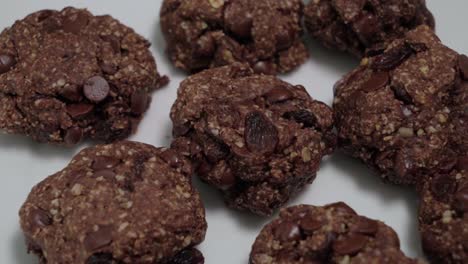 Oatmeal-raisin-cookies-with-chocolate-chips-on-white,-closeup-pan-right