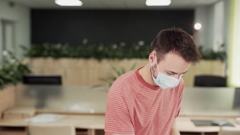 close-up-portrait-of-a-handsome-guy-office-worker-disinfecting-his-hands-in-a-medical-protective-mask