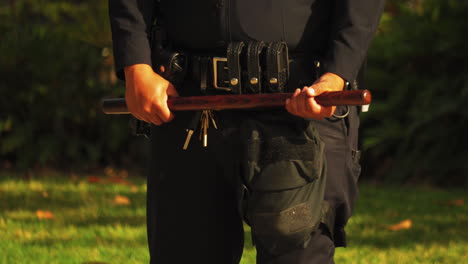 Police-Officer-Holding-Wooden-Baton-at-BLM-Protest,-Close-up-on-Hands