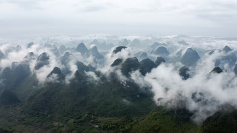 Amazing-karst-mountain-pinnacles-above-low-cloud,-Yangshuo-China,-aerial-view