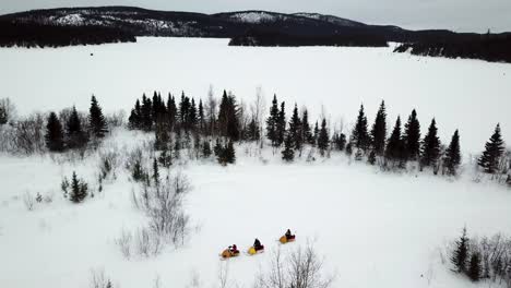 Aerial-image-of-a-snowmobile-rally-on-a-lake-and-in-the-woods-in-Chibougamau,-Quebec