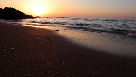 Calm-ocean-sea-water-waves-breaking-on-sandy-beach-at-sunset,-Tyre,-Lebanon,-static-low-angle