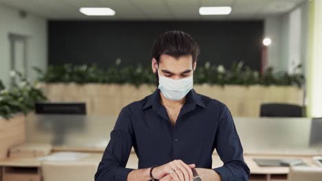 close-up-portrait-of-arab-office-worker-disinfecting-hands-in-medical-protective-mask