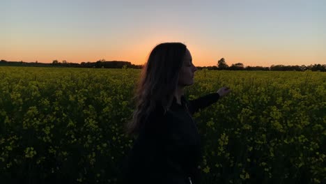 Beautiful-women-running-along-rapseed-field-during-sunset