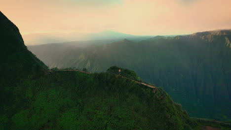 Man-running-at-stairway-to-heaven-with-epic-landscape-in-background,-aerial,-Hawaii