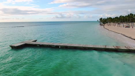 AERIAL-Over-Rustic-Wooden-Jetty-On-Tropical-Island-Beach
