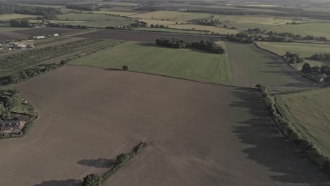 Aerial-view-golden-hour-rural-British-countryside-farmland-growth-sunrise-shadows-pull-back-pan-left