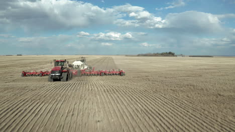 Seeding-Machinery-On-The-Broad-Farm-In-Saskatchewan,-Canada-On-A-Bright-Weather---fast-drone-shot