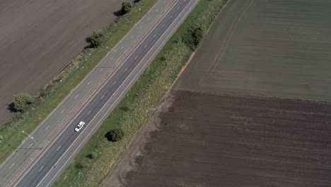 Aerial-view-over-head-British-farmland-countryside-East-Lancs-A580-highway-traffic-birds-eye-tilt-up-slow