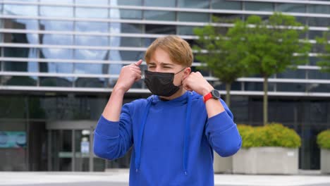 Young-teenager-difficult-takes-off-face-mask-in-the-center-of-the-city