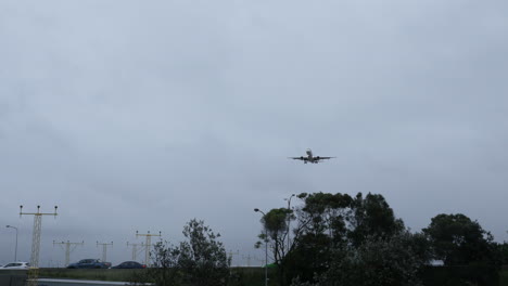 Plane-coming-into-land-at-Sydney-Airport-Australia-with-car-traffic-in-the-background-in-gray-stormy-weather-shot-in-4k