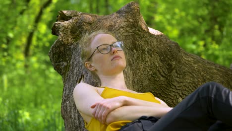 Close-up-shot-of-young-woman-lying-and-relaxing-on-the-tree-branch