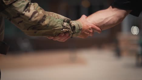 Military-man-and-civilian-grabbing-arms-shaking-hands-close-up-slow-motion