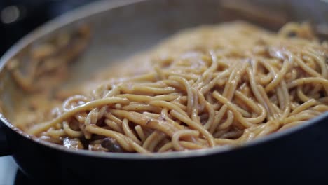 Mixing-Nutritious-Spaghetti-With-Sauce-And-Mushroom-In-A-Hot-Skillet---close-up