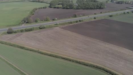 Aerial-view-across-British-farmland-countryside-East-Lancs-A580-highway-traffic-slow-pull-back