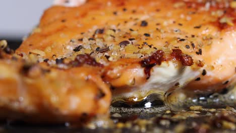 Sprinkling-Seasoning-And-Spices-To-Salmon-Fillet-Cooking-In-Oil---close-up