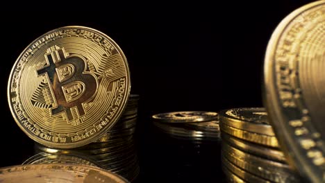Goldene-Bitcoin-münzen-Auf-Schwarzem-Reflektierendem-Glas,-4k-makroansicht,-Die-Sich-Rückwärts-Bewegt,-Kryptowährung