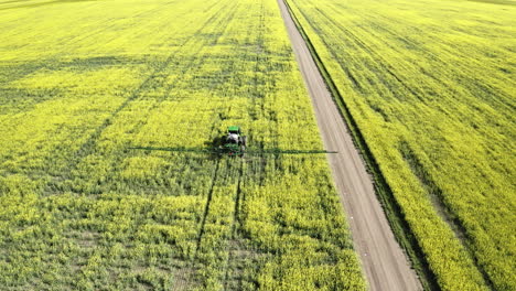 Farming-Tractor-Spraying-The-Beautiful-Yellow-Canola-Fields-In-Saskatchewan,-Canada