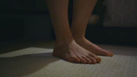 Close-up-of-a-woman's-feet-as-she-slowly-gets-out-of-bed-and-walks-out-of-frame