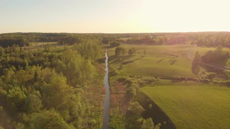 Drone-flying-forward-above-stream-in-northern-Europe-park-at-sunset