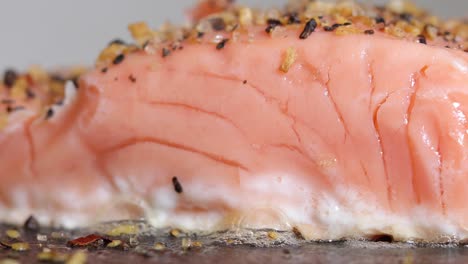Uncooked-raw-single-piece-of-salmon-sushi-sizzling-and-cooking,-close-up-side-view-pan-right