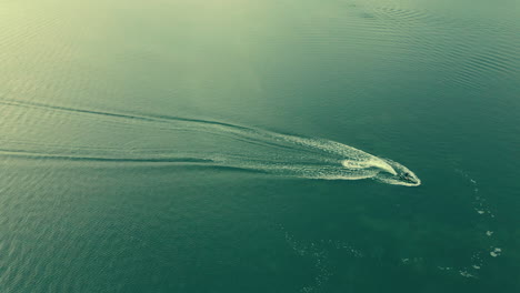 Aerial-view-showing-floating-jetski-on-green-sea-during-sunny-day-in-slow-motion
