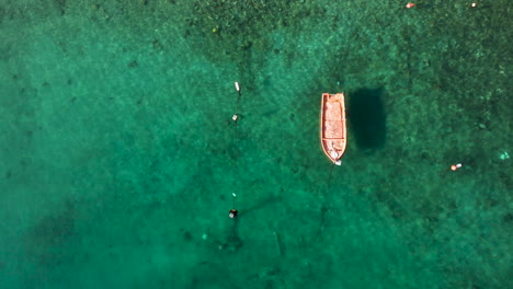 A-Wooden-Boat-Floating-On-The-Turquoise-Blue-Sea-Water-In-Greece---top-aerial
