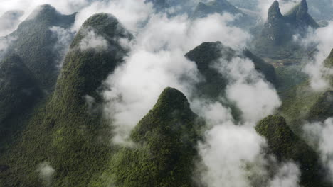 Dramatic-karst-mountains-in-clouds,-high-aerial-view
