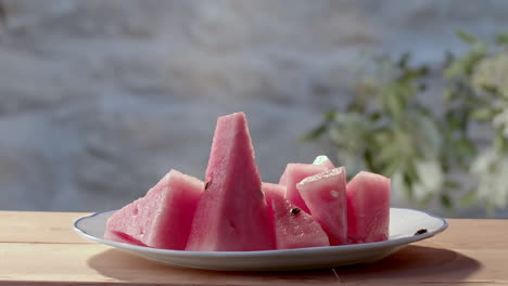 Slice-of-watermelon-dropped-onto-serving-plate,-close-up