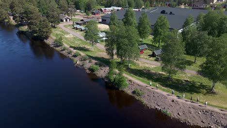 Reversed-drone-footage-revealing-a-group-of-runners,-running-alongside-of-a-river-in-Dalarna-Sweden