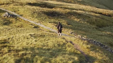 Hiker-walking-down-the-slope-of-the-Kinder-Scout-moorland-plateau,-Peak-District,-Derbyshire