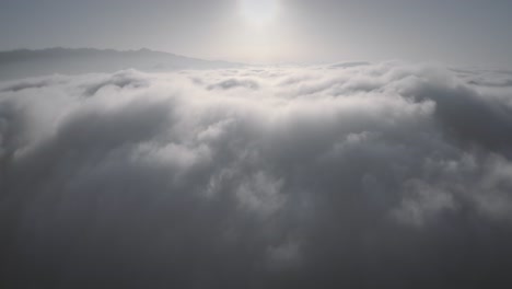 Aufsteigende-Luftaufnahmen-über-Einer-Dicken-Wolkendecke-über-Berggipfeln