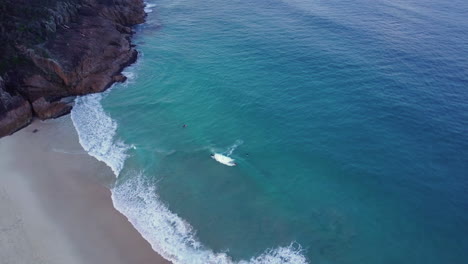 High-aerial-view-of-bodyboarders-riding-the-waves-at-Shoal-Bay,-Australia,-drone