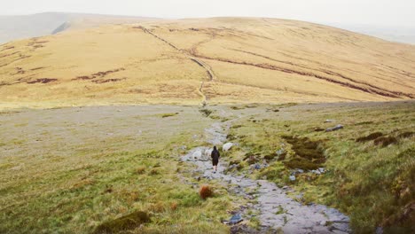 Person-walks-down-hiking-path-through-expansive-moorland,-Peak-District,-Derbyshire