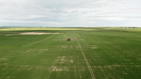 Farm-Machinery-Spraying-Green-Wheat-Fields-In-Saskatchewan,-Canada---aerial-drone