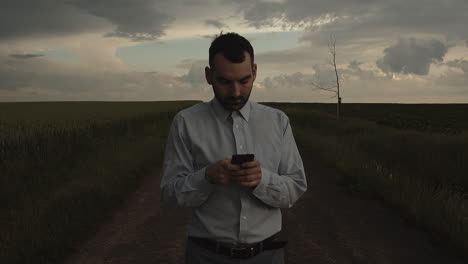 Manager-using-cellphone-outside-in-middle-of-fields-and-taking-photo,-front-view