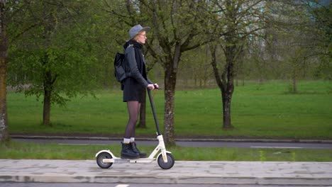 Following-side-shot-of-stylish-woman-driving-an-electric-scooter