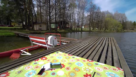 pedal-boat-parked-at-a-wooden-pier-on-a-pond-with-blanket-and-a-book-on-top