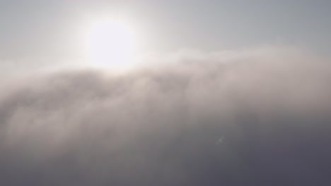 Elevándose-A-Través-De-Las-Nubes,-Vista-Aérea-Del-Sol-Y-Los-Picos-De-Las-Montañas-Por-Encima-De-Las-Nubes