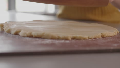 rolling-out-pie-dough-on-kitchen-countertop