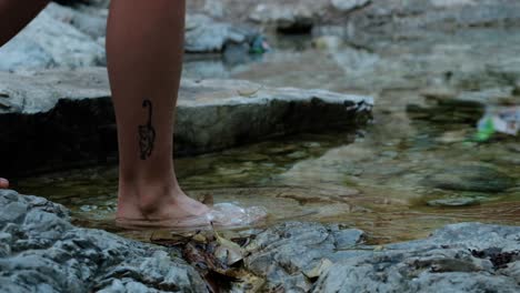 Extreme-close-up-of-a-females-feet-crossing-barefoot-a-stream-in-slow-motion