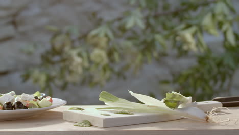 Scallions-dropped-on-cutting-board-near-salad,-slow-motion