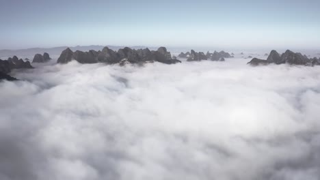 Xianggong-Chinese-mountain-peaks-rising-up-above-clouds,-high-aerial-view