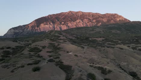 Utah-Mountains-panorama-at-sunset,-drone-rising-up-to-show-sunlit-peak