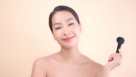Happy-confident-asian-female-with-powder-brush-after-makeup-makeover,-close-up-slowmotion