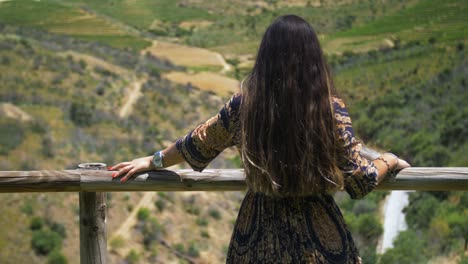 Slow-motion-of-woman-in-blue-and-gold-dress-enjoying-nature-in-wooden-handrail