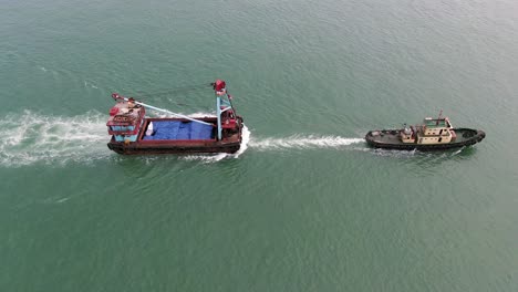 Remolcador-Tirando-De-Una-Pequeña-Barcaza-En-La-Bahía-De-Hong-Kong,-Vista-Aérea